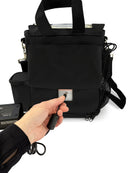 Hand plugging power cord into black Inogen oxygen concentrator carry bag